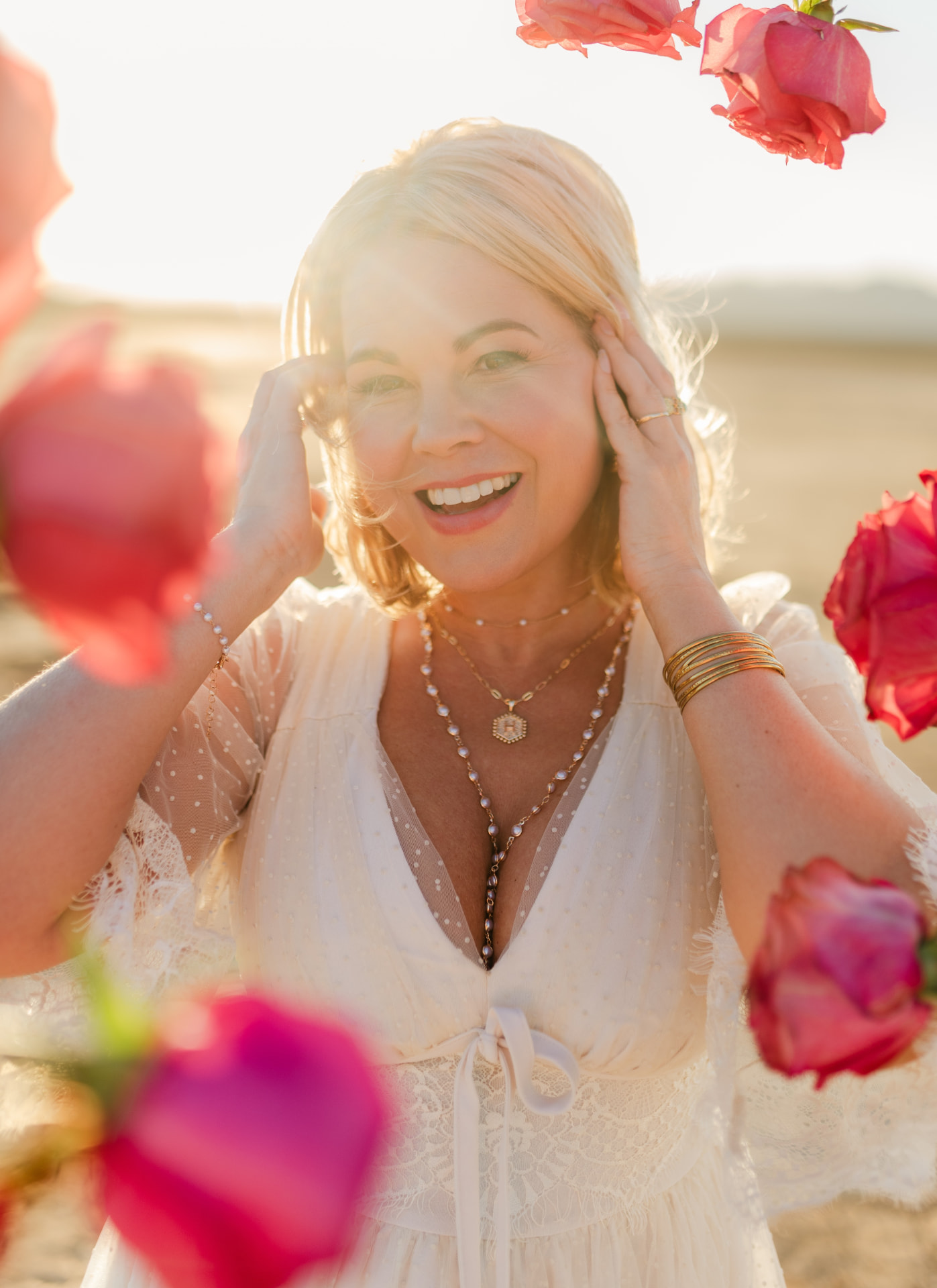 Nina Moon smiling among pink roses in golden desert light
